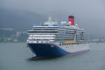 Modern cruiseship cruise ship liner Luminiosa anchored in Juneau bay, Alaska during heavy rain and...