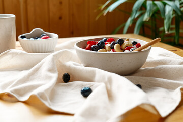 Coconut yogurt granola with strawberry, blueberry and cashew in white bowl. Concept of healthy breakfast, vegetarian meal, dieting, weight loss, healthy eating.