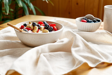 Coconut yogurt granola with strawberry, blueberry and cashew in white bowl. Concept of healthy breakfast, vegetarian meal, dieting, weight loss, healthy eating.