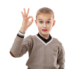 Portrait of blonde seven year old boy shows ok okay gesture and smiling to the camera isolated on white background. Attractive child in brown sweater posing in studio.