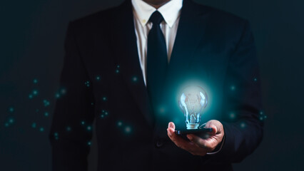 Businessman is using smartphone bright light bulb against dark blue background. Business email ideas concept.