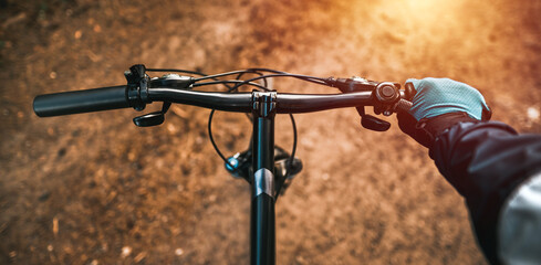 First-person view of handling the bicycle on the forest road in the city towards sunlight. Concept...
