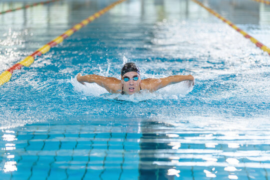 Front view of a powerful elite female swimmer competitor performing butterfly swim technique, arm stroke movements. Swim fly and dolphin kick concept.