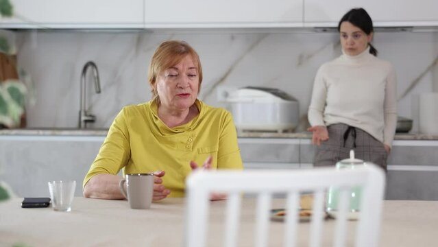 Frustrated elderly mother having tense conversation with her daughter 