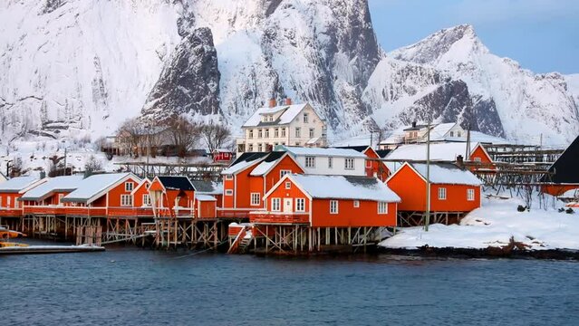 Cold morning view of popular tourist destination - Lofoten Islands. Red houses on the shore of Norwegian sea. Wonderful winter scene of Sakrisoy fishing village. Full HD video (High Definition).