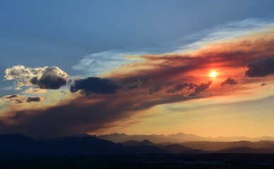 colorful sunset over the front range of the rocky mountains through the smoky haze of the spring creek wildfires near parachute, as seen from broomfield, colorado