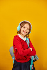 Happy schoolgirl with backpack, headphone having fun