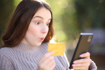 Surprised woman buying online in a park