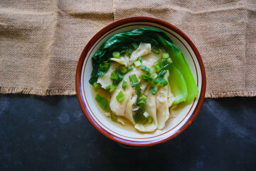 wonton soup or pangsit or dumplings soup and vegetable. wonton is traditional Chinese food of...