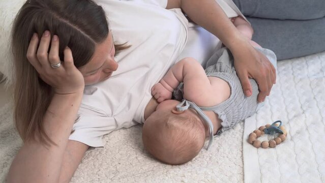 Happy mother breastfeeding her baby, talking and gently touching her in the bedroom. A woman is breastfeeding a newborn. The concept of breastfeeding. The baby eats mother's milk. A young woman is