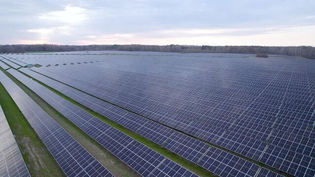Vast solar farm with long rows of PV panels in Polish countryside, aerial