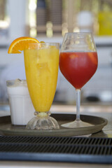 Glasses of aperol spritz and fresh squeezed orange juice on the bar counter, summer drinks for refreshment