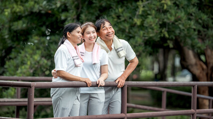Beautiful Asian woman taking her father and mother to exercise in the park happily, with a smile. Young woman invites parents to exercise, warm family, good health. concept health care life insurance.
