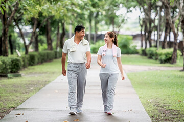 Young beautiful asian woman jogging with her father in park happily, with a smile. Asian woman jogging with her father for health care, park exercise, health care. concept health care life insurance.