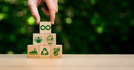 circular economy icons in wooden cubes. economic system that aims to minimize waste and maximize...