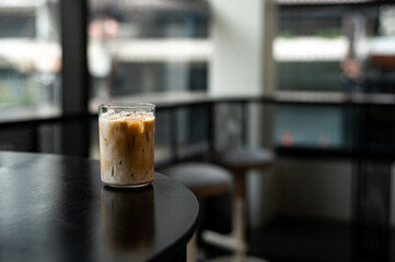 Iced coffee in glass on table in coffee shop blur background.