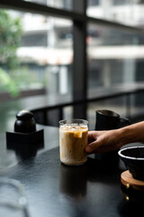 Iced coffee in glass on table in coffee shop blur background.