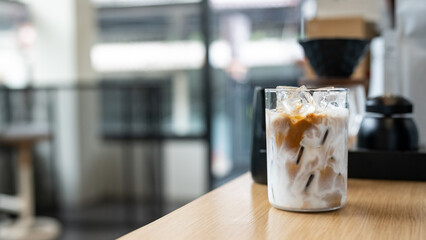 Iced coffee in glass on table in coffee shop blur background.