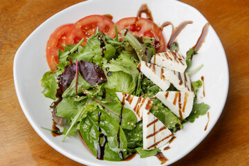 Traditional greek salad in the plate - lettuce, feta cheese and tomato slices with olive oil