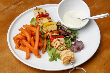 Greek souvlaki, sweet potatoe and tzatziki yogurt dip served on the plate in the restaurant