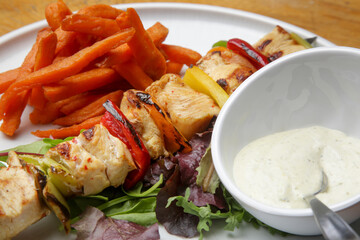 Greek souvlaki, sweet potatoe and tzatziki yogurt dip served on the plate in the restaurant