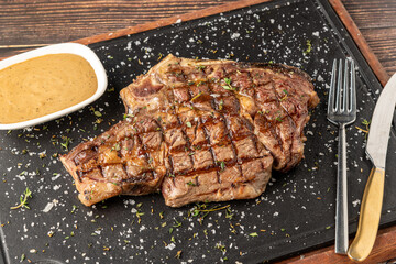 Grilled tomahawk steak on stone cutting board in steakhouse restaurant