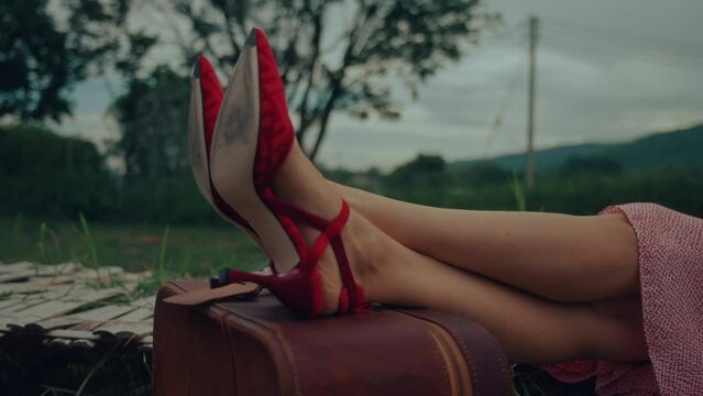 Female feet in red shoes on retro suitcase