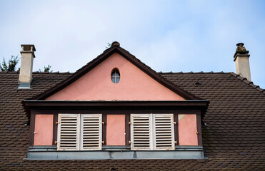 A magnificent house with a unique facade and a chimney stands tall against the clear blue sky, showcasing its remarkable architecture and roof.
