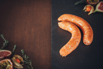 Delicious chipolata sausages on a slate and wooden background. Raw meat prepared for cooking. Black slate / wood background. Space for text