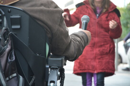 Handicap&eacute; en fauteuil roulant tenant un micro face &agrave; une femme habill&eacute;e en manteau rouge
