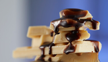 liquid dark chocolate slowly flows over white chocolate pieces. sweet food close-up. High quality 4k footage