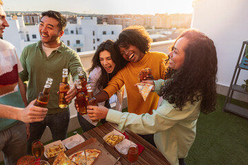 group of diverse friends partying on rooftop drinking alcohol and eating, toasting with beers - Powered by Adobe