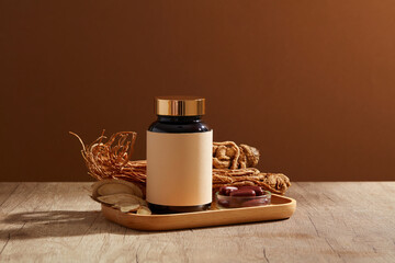 A glass jar without label arranged with Angelica root and Bai Zhu on the tray. A bowl of red medicine displayed. Herbs are good for health. Mockup with empty label