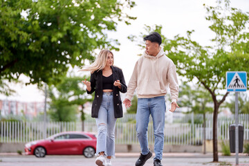 Fototapeta premium Man and woman talking while walking outdoors on the street.