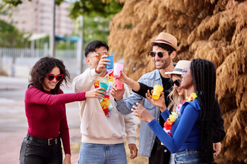 Happy friends drinking while partying outdoors. Party, carnival and friendship concept.