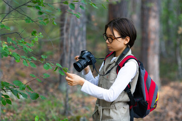 Girl naturalist taking a photo in the forest.