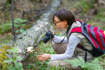 Girl naturalist studies and taking a photo in the forest.
