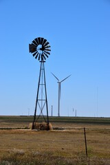 Traditional old windmill in a meadow with a modern wind turbine in the background