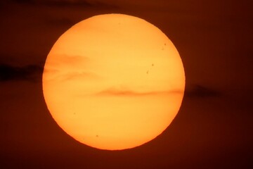 Stunning sunset with orange sky, illuminated by the setting sun and fluffy dark clouds