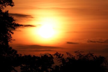 Stunning sunset with orange sky, illuminated by the setting sun and fluffy dark clouds