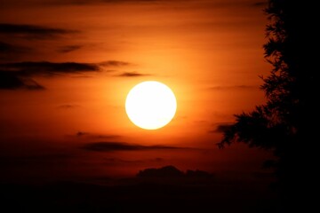 Stunning sunset with orange sky, illuminated by the setting sun and fluffy dark clouds