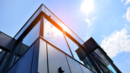 Graphite facade and large windows on a fragment of an office building against a blue sky. Modern...