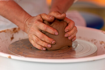 Close-up of a woman's hands beautifully and smoothly forming a brown clay vase on a potter's wheel.