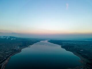 Fototapeta premium Aerial view of a beautiful river at sunset with an orange sky in the background