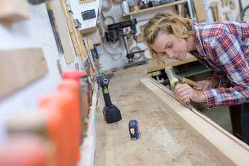 woman using hammer and chisel to cut groove from wood