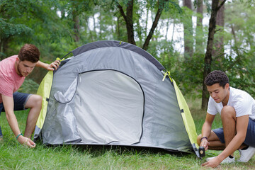 two young men erecting tent