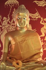 Fototapeta premium a golden buddha sitting next to a red wall with flowers