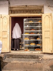 Buyer in a traditional bakery, looking in at the display of fresh baked goods in the open window