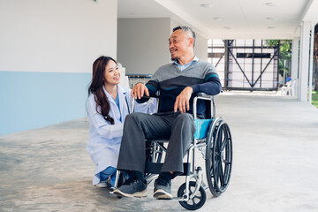 Obraz premium Asian young doctor taking care and talking mature female patient sitting on wheelchair in hospital. Healthcare concept.