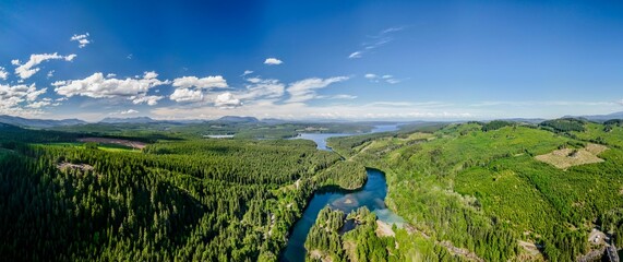 Panoramic view of a river surrounded by lush greenery under a blue cloudy sky